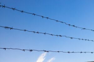Barbed wire fence against blue sky. Dangerous area.