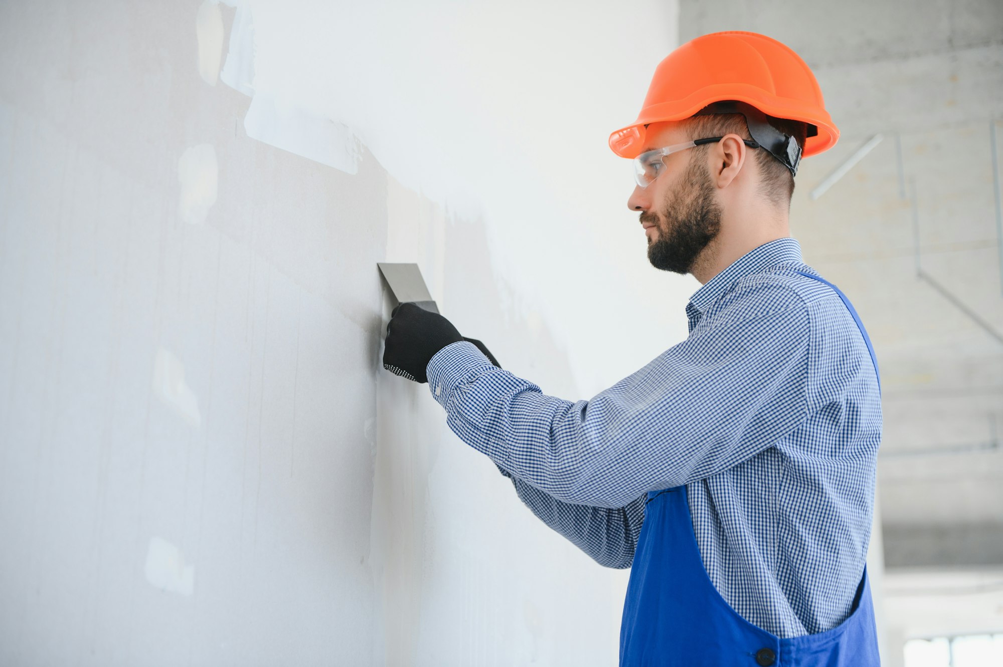 man drywall worker or plasterer sanding and smoothing a plasterboard walls