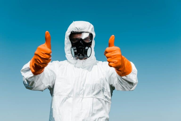 exterminator in protective mask and uniform standing and showing thumbs up