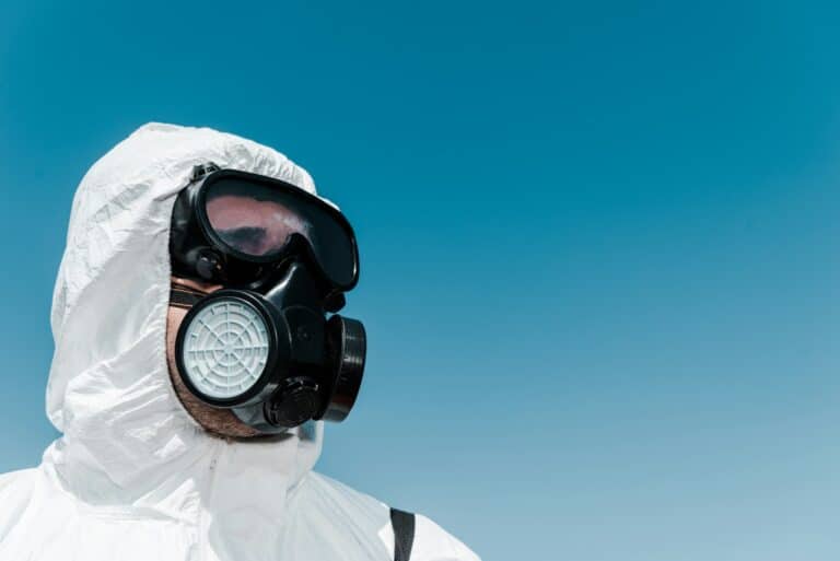 exterminator in white uniform and protective mask against blue sky